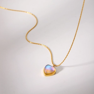 Gros plan détaillé du pendentif cœur en or 18 carats avec une pierre de lune irisée
