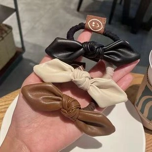 Close-up of black, cream and brown PU leather bow hair ties with elastic bands