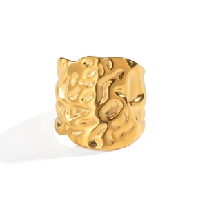 Detailed view of the wide golden ring featuring a unique geometric hammered texture