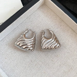 Macro shot of silver ribbed teardrop earrings with high-polish metallic finish and clicker