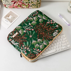 Detail view of green quilted laptop sleeve with daisy embroidery and zipper storage