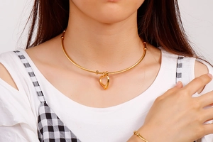 Close-up of golden hollow heart necklace and wire choker set on model's neck