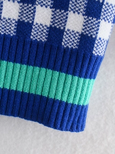 Macro view of knit cardigan texture with mint green checkerboard pattern and ribbed cuffs
