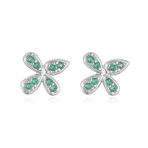 Detailed macro view of bow earrings with green crystals on a polished silver base