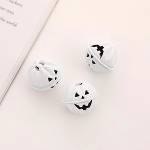 Three white pumpkin-shaped metal bells with Halloween jack-o-lantern faces on a clean surface