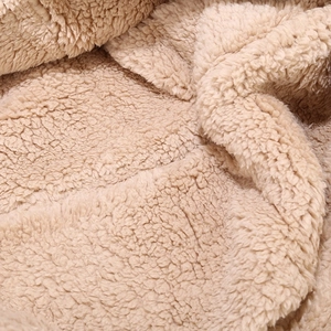 Close-up of soft beige sherpa fleece material showing thick and warm plush texture