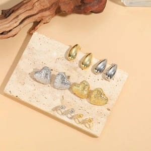 Detail view of heart and water drop earrings on a stone slab with natural wood texture