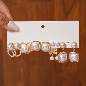 Detailed close-up of set with pearl earrings in waterdrop and geometric gold shapes