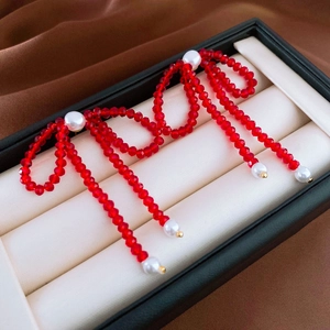 Macro detail of red beaded bow earrings with white pearls on a luxury jewelry box