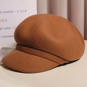 Detailed macro view of brown wool baker boy hat with black sequin band and thick warm texture