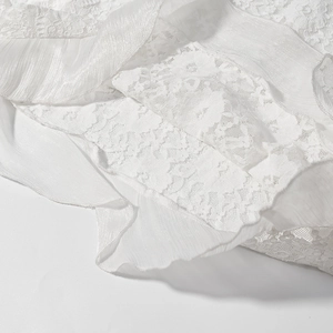 Gros plan sur la dentelle florale blanche et le tissu en mousseline plissée de la robe