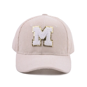 Detail der beigen Cord-Baseballkappe mit M-Patch und goldener Paillettenstickerei