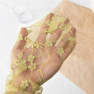 Detail of sheer yellow lace socks with floral embroidery and breathable mesh texture