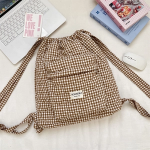 Detailed close-up of brown and white checkered quilted backpack with heart embroidery