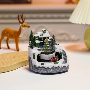 Detail of Christmas snow village resin house with train track and micro trees on tray