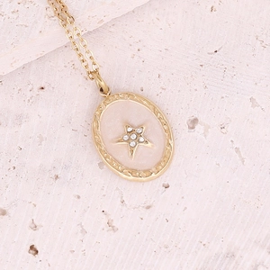 Detailed macro of gold star pendant with zircon on a beige background surface