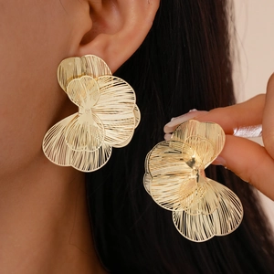 Close-up of golden hollow petal earrings showing detailed metallic layering on ear