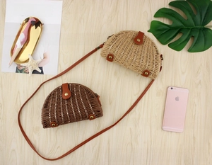 Detail of semi-circular straw crossbody bags in beige and coffee with leather straps