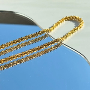 18k gold plated stainless steel star chain necklace with woven texture on reflective mirror