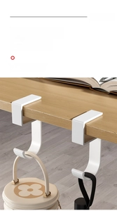 Close-up of white U-shaped desk hook for bags clamped on a wooden table edge