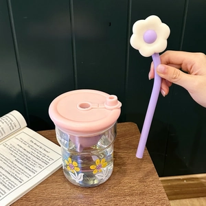 Détail d'un gobelet en verre avec motifs floraux jaunes et une paille violette
