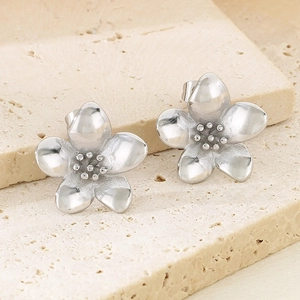 Detailed macro view of silver floral petal earrings on natural sandstone base