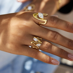 Primer plano de anillos ondulados bañados en oro con detalles de circonitas en talla marquesa