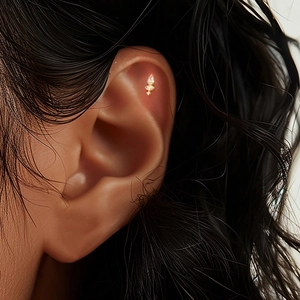 Close-up of golden marquise star cartilage stud earring on ear with diamond accent