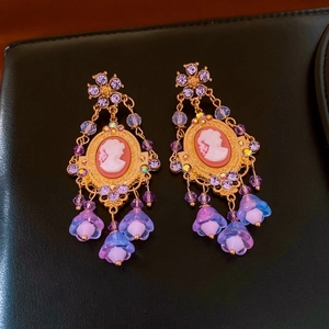 Detailed close-up of vintage cameo earrings with purple rhinestones and floral tassel charms