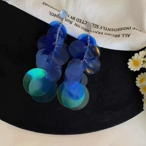 Détail de boucles d'oreilles à pompons avec sequins bleus et chaînes argentées