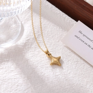 Fashionable gold titanium steel mini star pendant necklace on a soft white texture background
