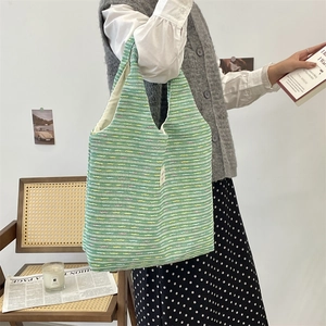Detail of green knit tote bag with colorful striped texture and woven side label