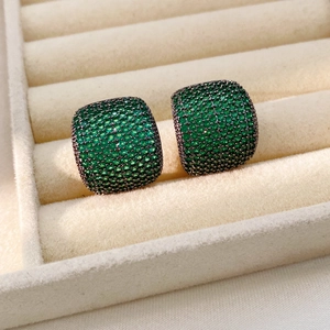 Détail macro de boucles d'oreilles vintage carrées avec zircons verts pavés