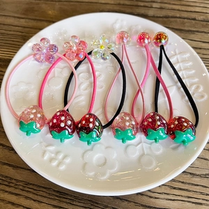 Colorful strawberry and flower elastic hair ties for kids displayed on a ceramic plate