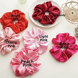 Detail of silk satin scrunchies in shades of red and pink on an elegant ceramic plate