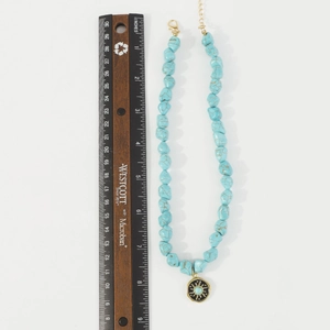 Macro view of bohemian turquoise beaded necklace with sun pattern pendant and scale