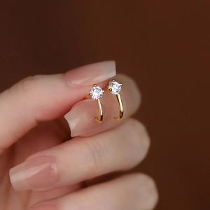 Elegant s925 silver curved gold stud earrings with cubic zirconia held by hand