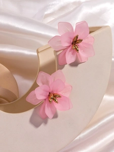 Macro detail of pink matte acrylic flower earrings with gold stamens on silk
