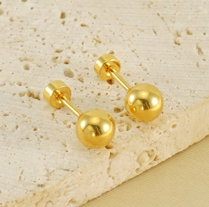 Detailed shot of gold ball stud earrings featuring a screw flat back on stone texture
