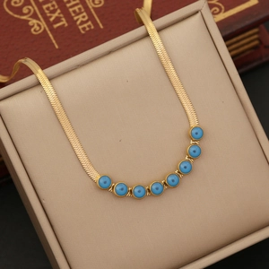 Detail of gold snake chain with seven blue evil eye charms against a vintage book