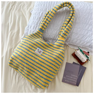 Detail of soft striped plush tote bag with yellow and blue stripes on white bedding