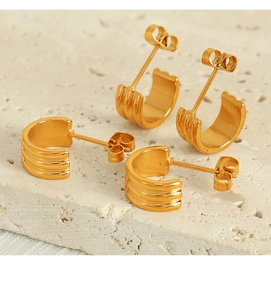 Détail macro de boucles d'oreilles créoles dorées à trois couches sur fond de pierre