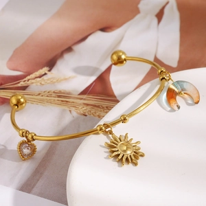 Dettaglio del bracciale a C placcato oro 18K con ciondoli a sole, luna e cuore di cristallo