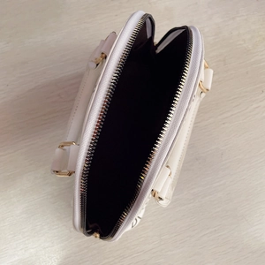 Macro view of white mini tote bag showing gold zipper detail and spacious inner compartment