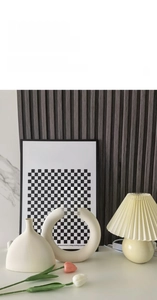 Minimalist white hollow ceramic vase and lamp set on a wooden table with tulips