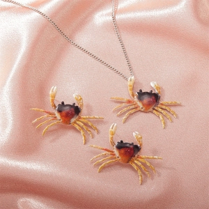 Detalle de collar y pendientes de cangrejo sobre tela de seda color rosa