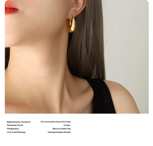 Detailed view of U-shaped gold plated titanium earrings worn by a model