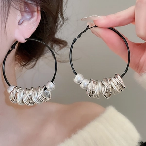Detail of twisted leather cord earrings with silver metallic rings and white bead accents