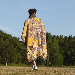 Detailed close-up of Bohemian yellow woven camping blanket with colorful fringe tassels