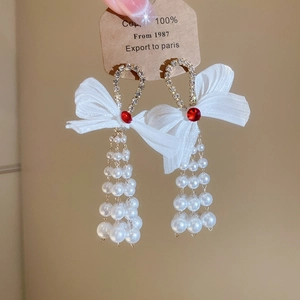 Detail of bowknot tassel earrings with red gemstones and white pearl drops